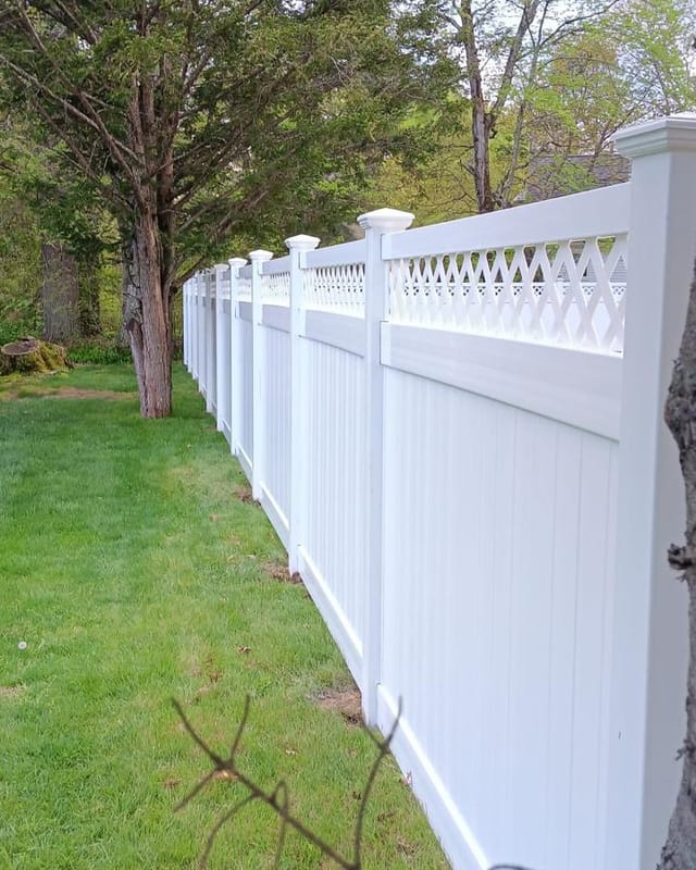 Long run of white vinyl privacy fence receding across a lawn