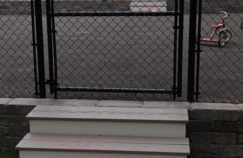 Black chain-link fence and gate installed beside deck steps