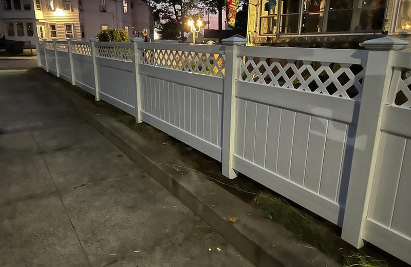 White vinyl lattice-top fence lining a paved walkway