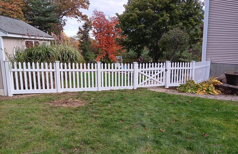 White vinyl picket fence with a walk gate in a residential yard
