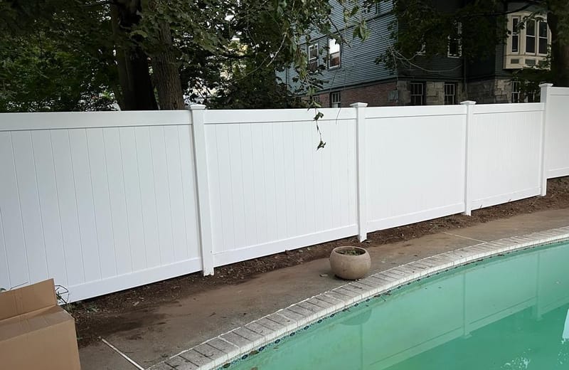 White vinyl privacy fence enclosing an in-ground pool patio
